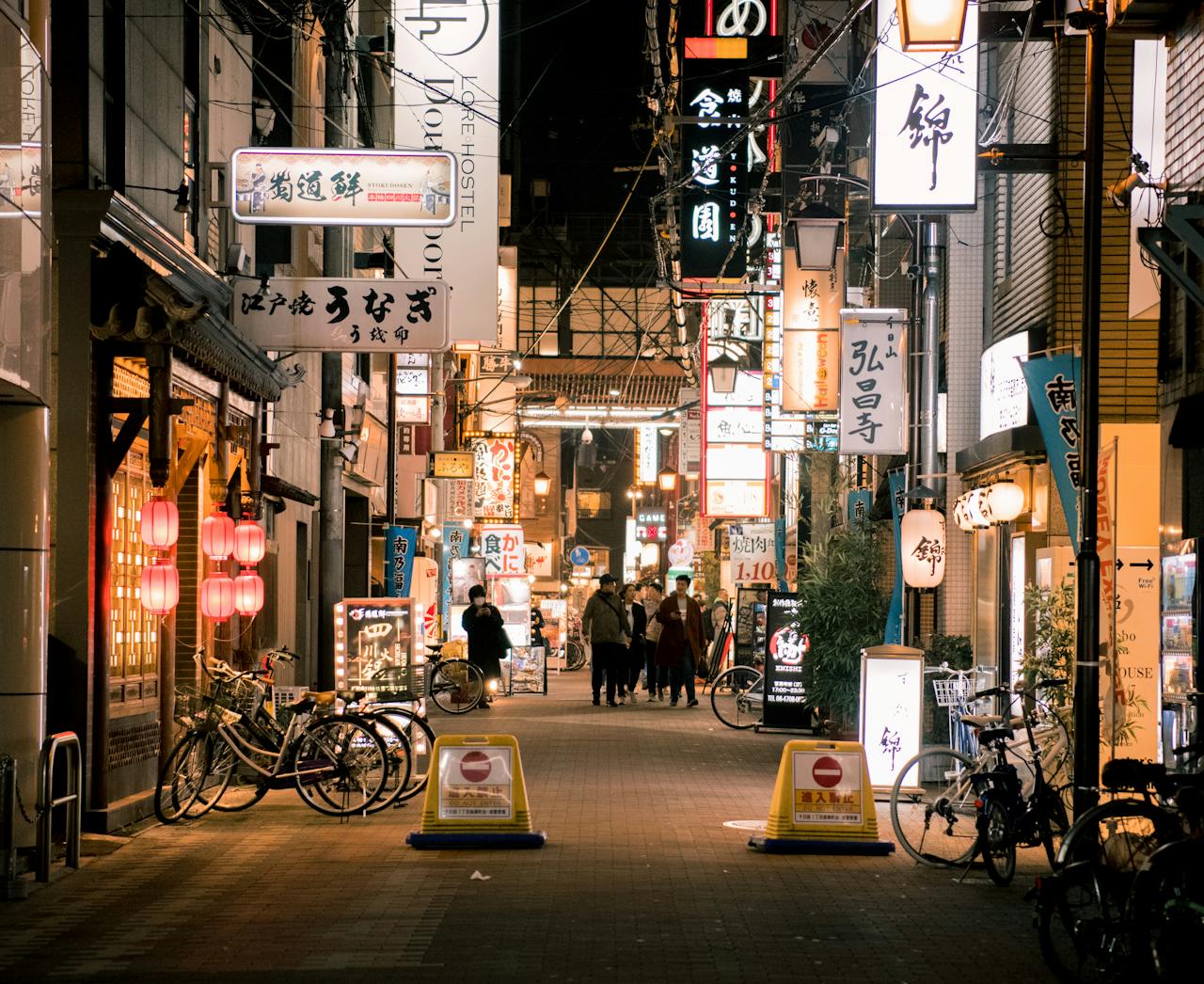services-01 Bustling evening scene of Osaka's vibrant shopping street with illuminated signs and people walking.